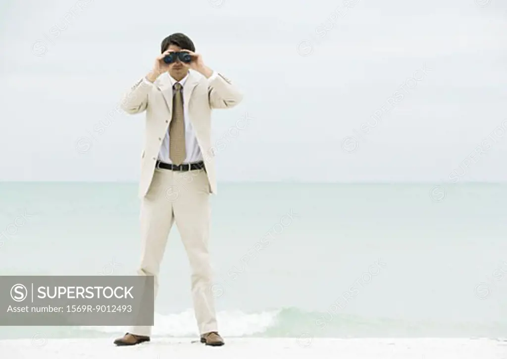Businessman looking through binoculars, facing camera