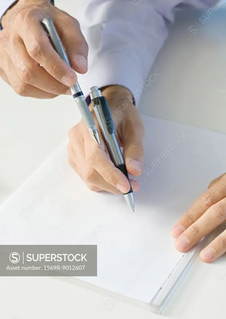 Businessmen holding pens over paper