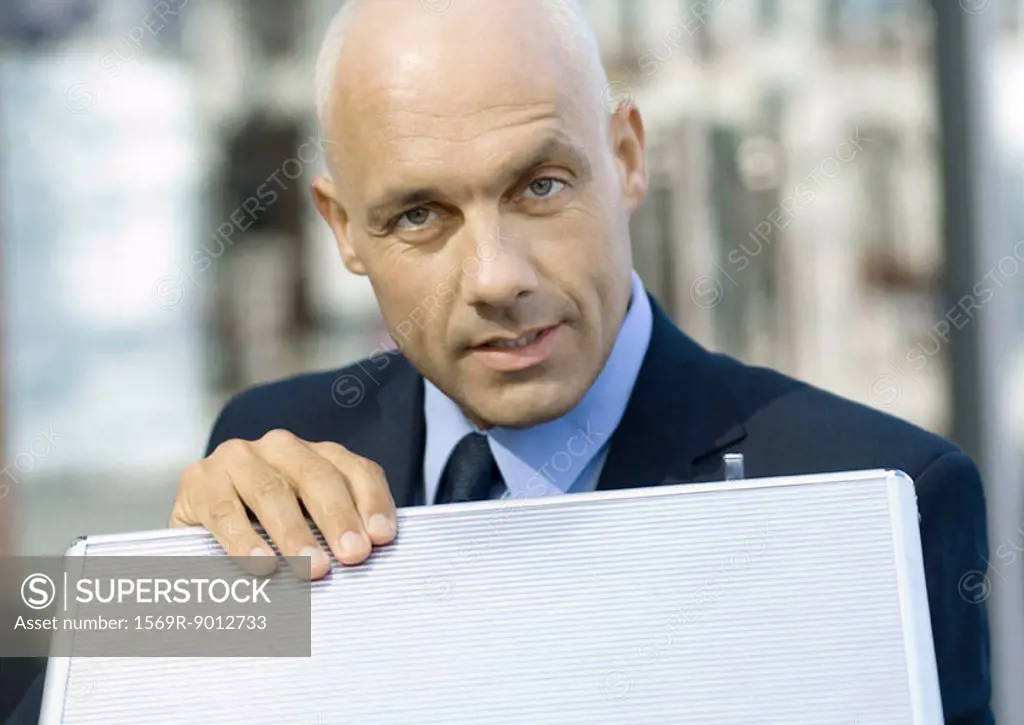 Businessman with hand on briefcase, looking at camera