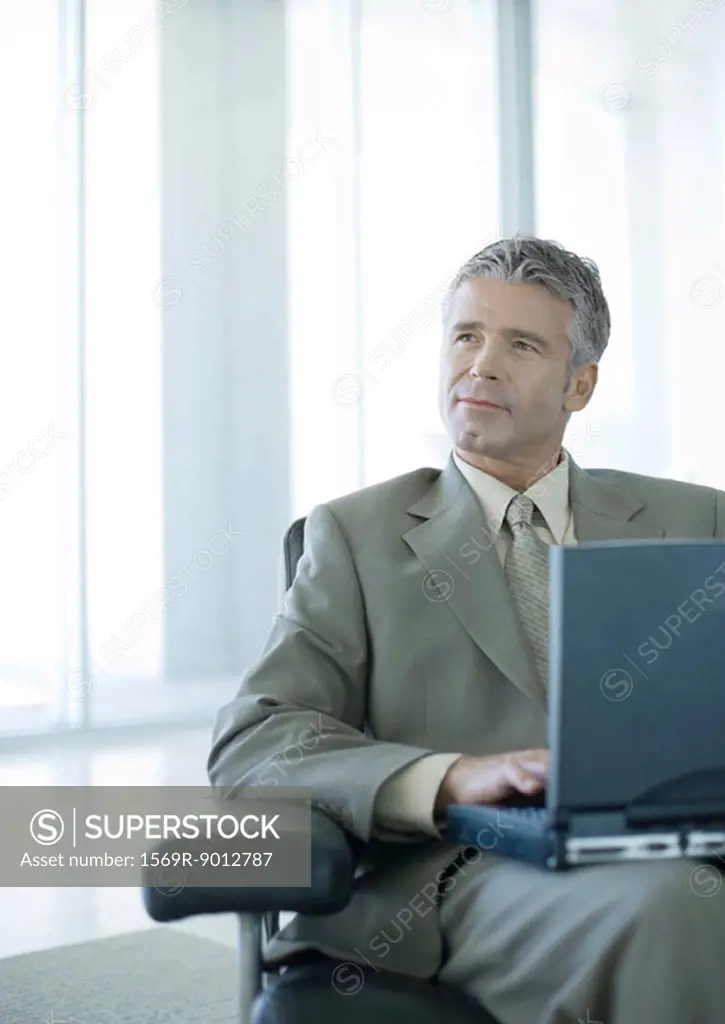 Businessman using laptop in office lobby