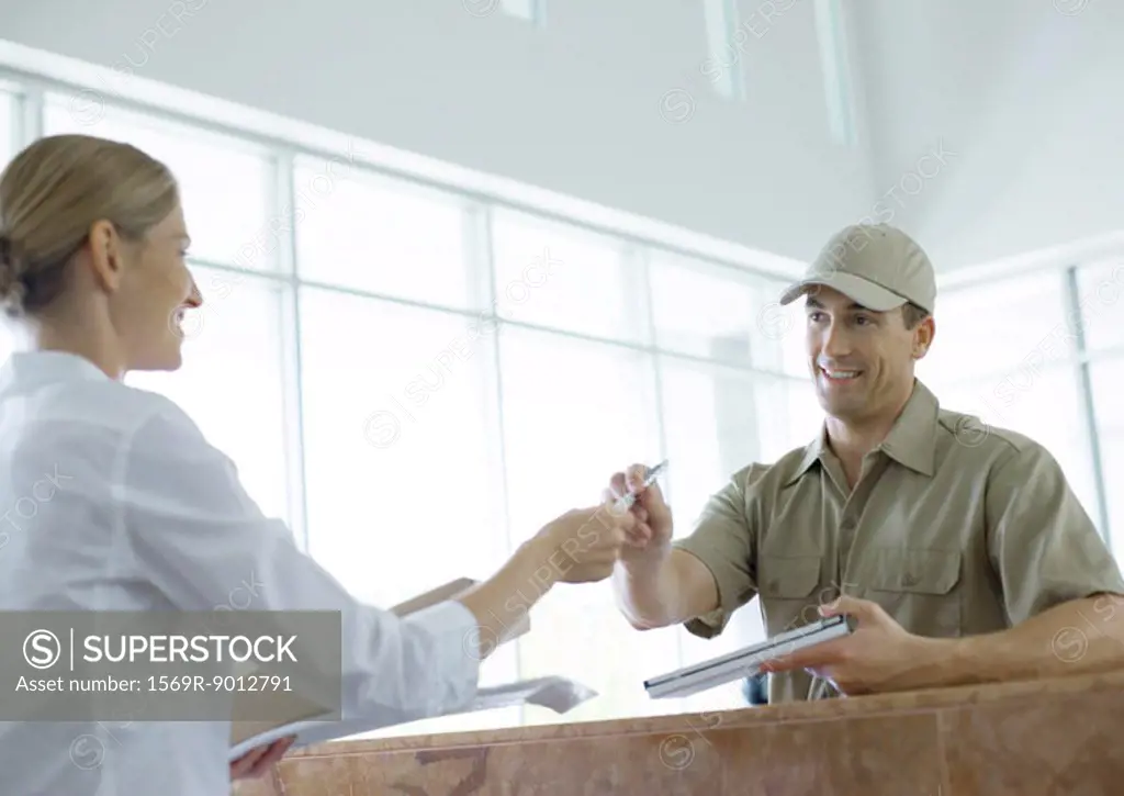 Receptionist handing pen to delivery man