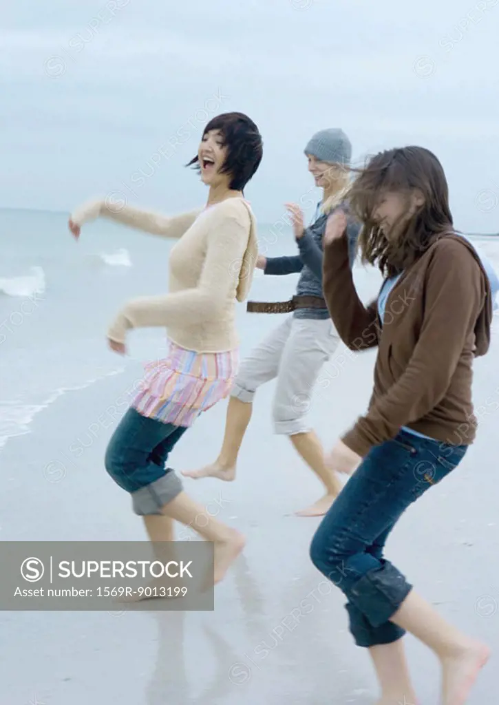 Three young women running toward surf