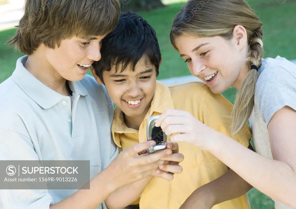 Three preteen friends looking at cell phone