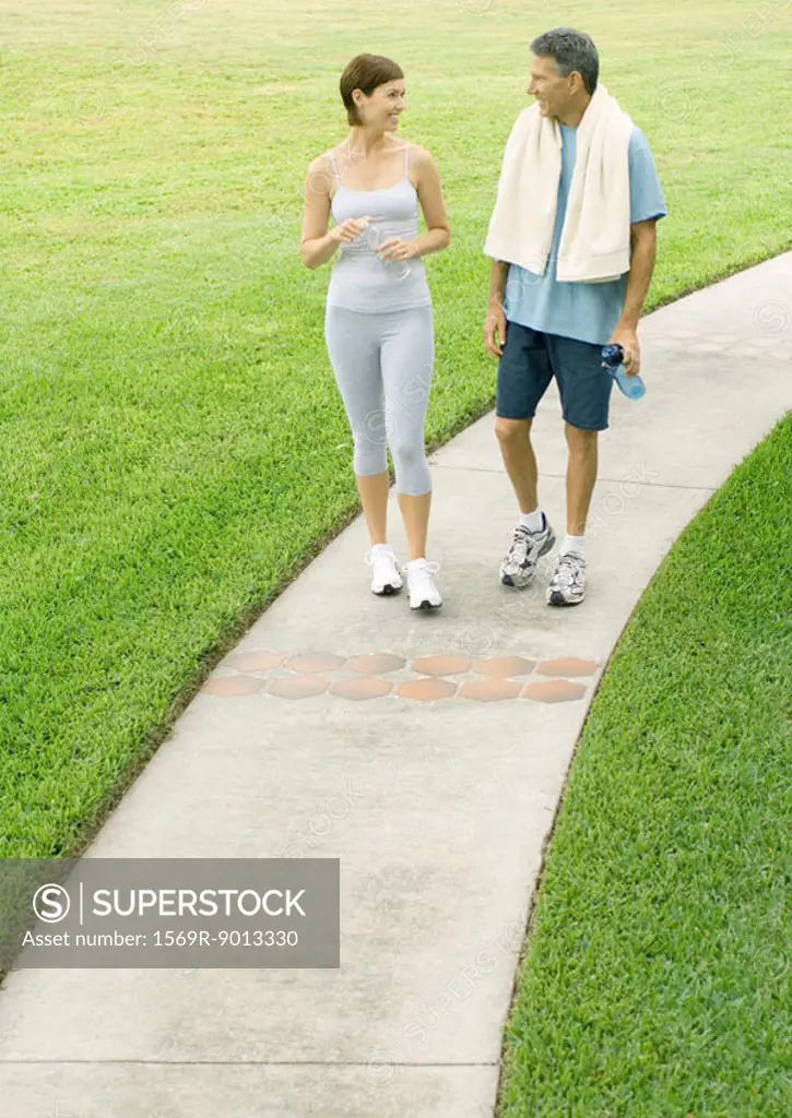 Mature couple walking on sidewalk in workout clothes