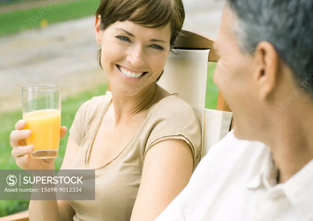Woman holding glass of orange juice, looking at husband