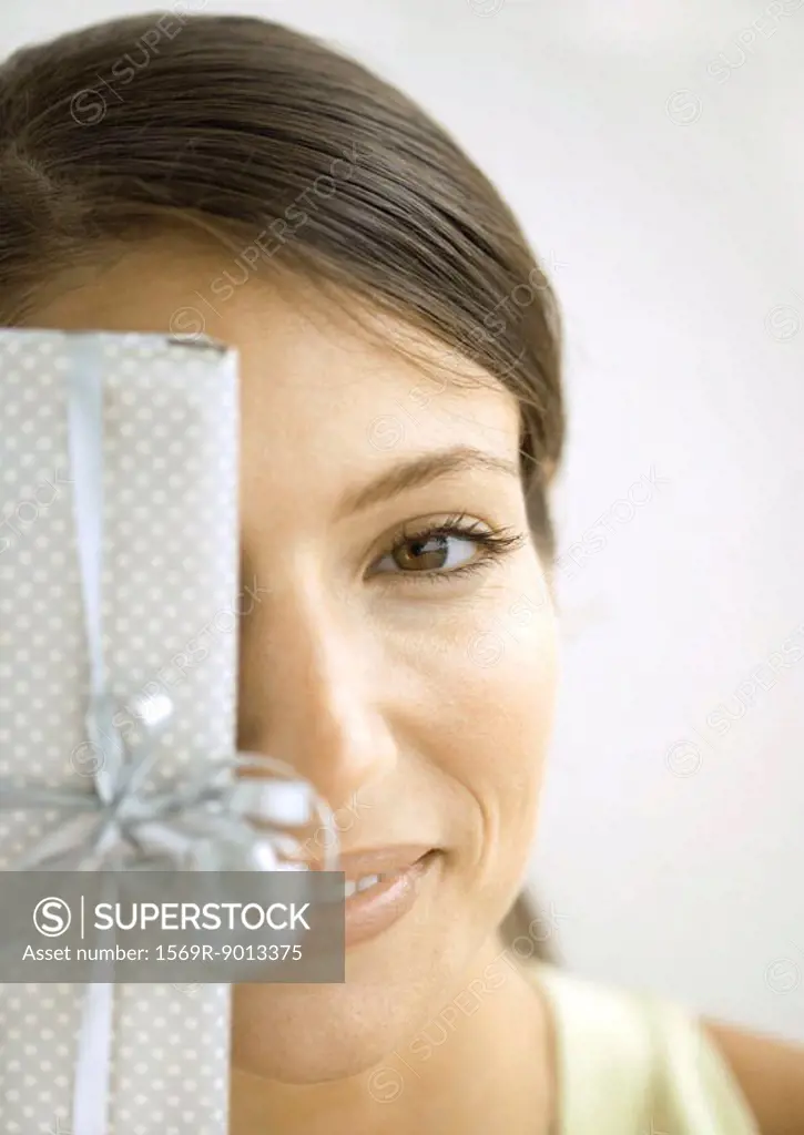 Woman holding gift in front of face