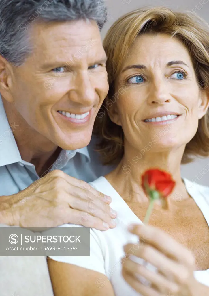 Mature couple, woman holding rose bud