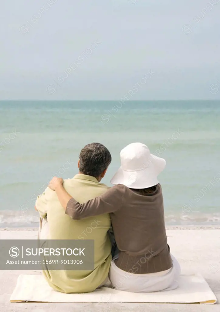 Couple sitting on beach, looking at sea, rear view