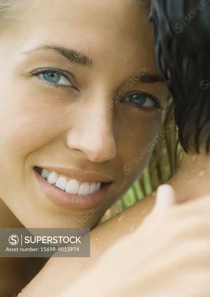 Woman embracing man, smiling at camera
