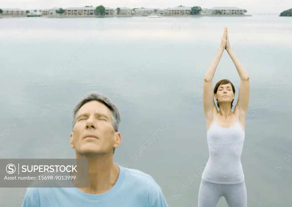 Couple doing relaxation exercises by edge of water