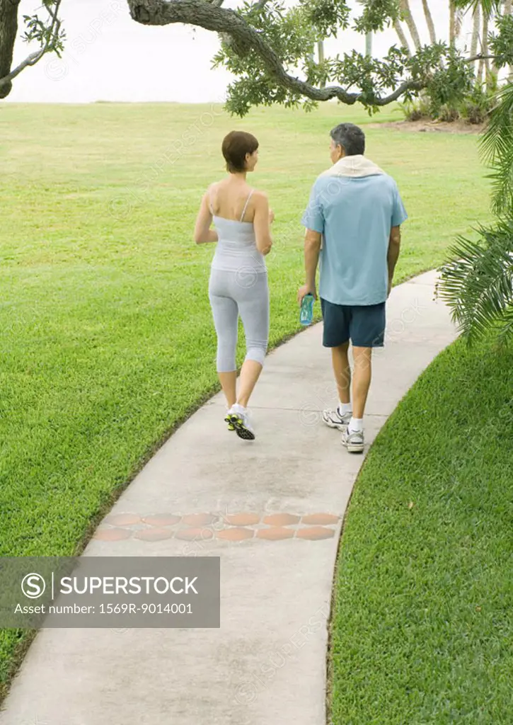 Couple in workout clothes walking on walkway, rear view