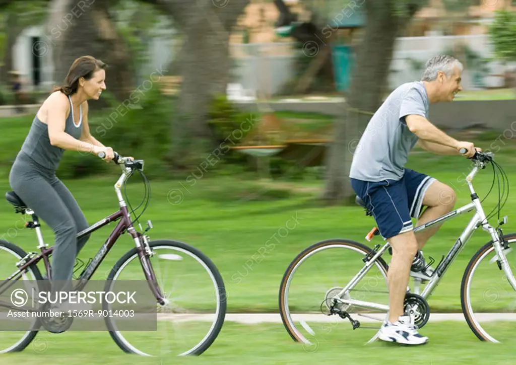 Mature couple riding bikes, side view