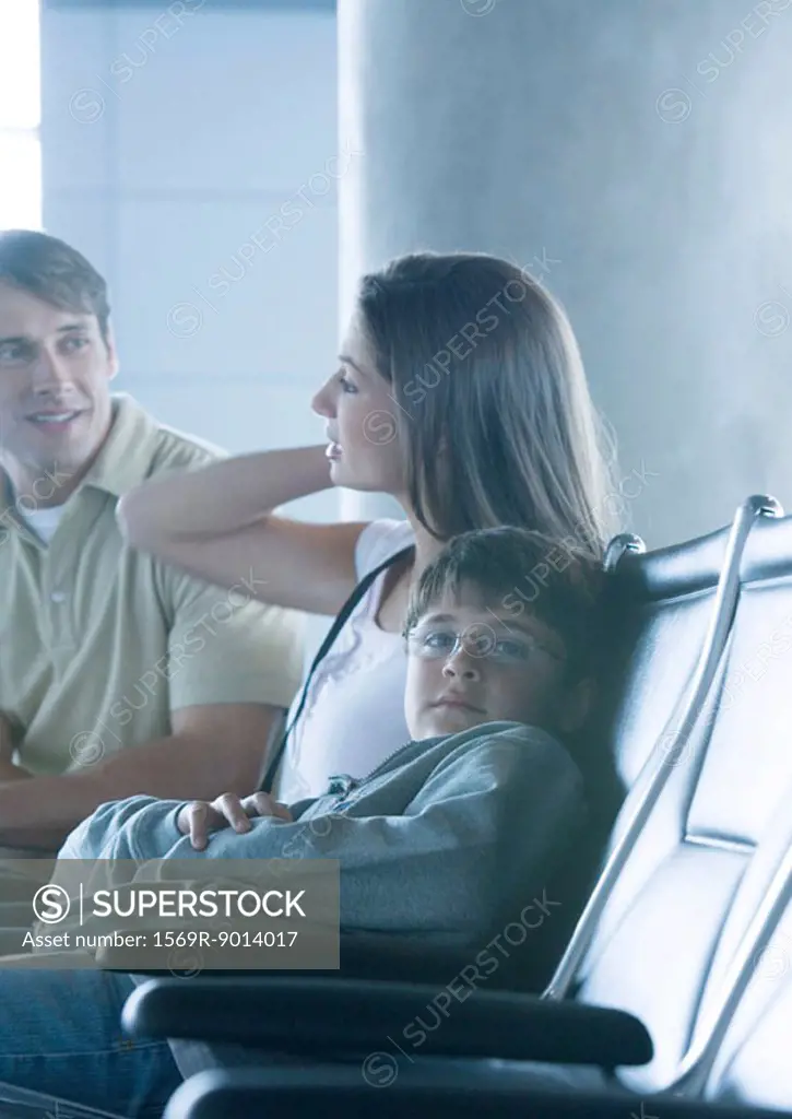 Family sitting in airport lounge, boy looking at camera