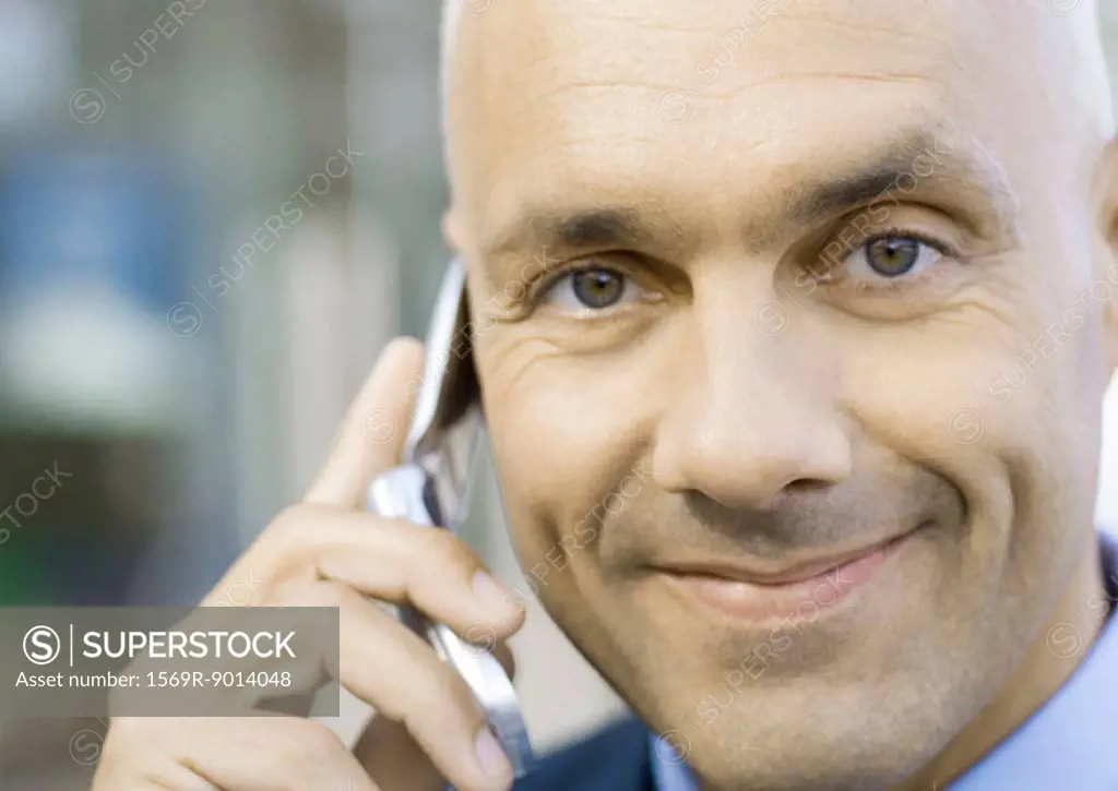 Businessman using cell phone, smiling
