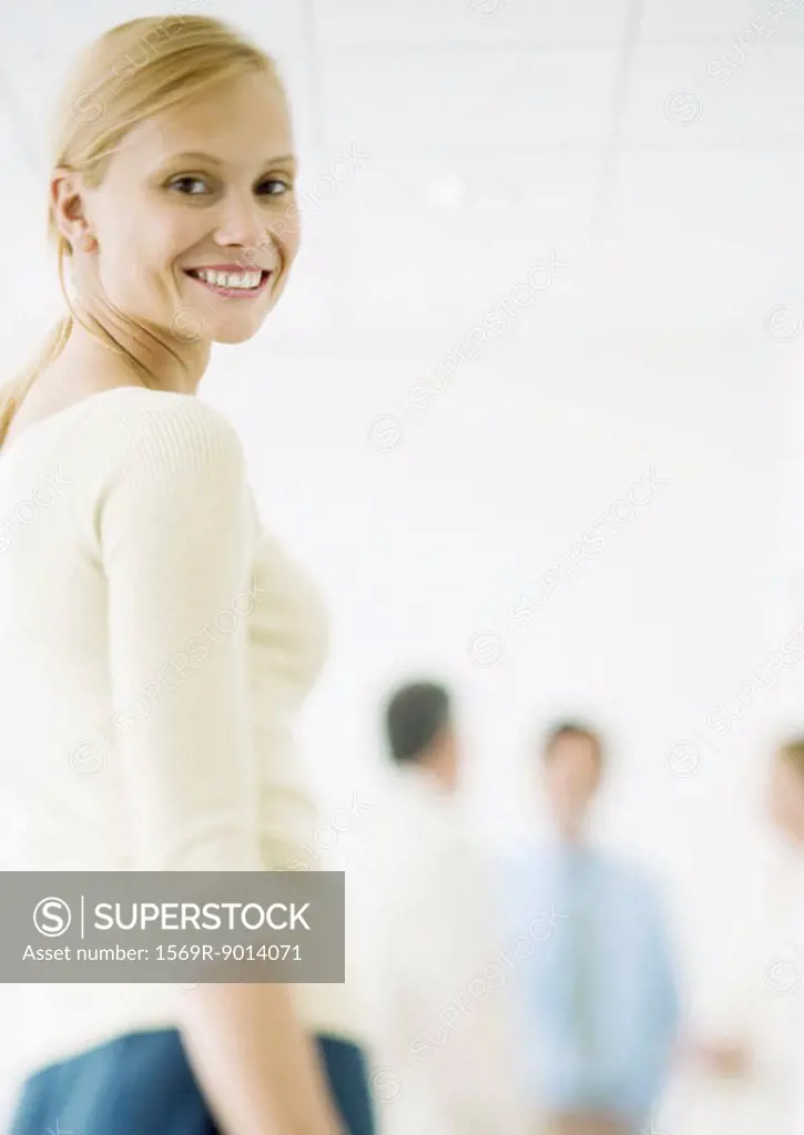 Young businesswoman, colleagues standing in background