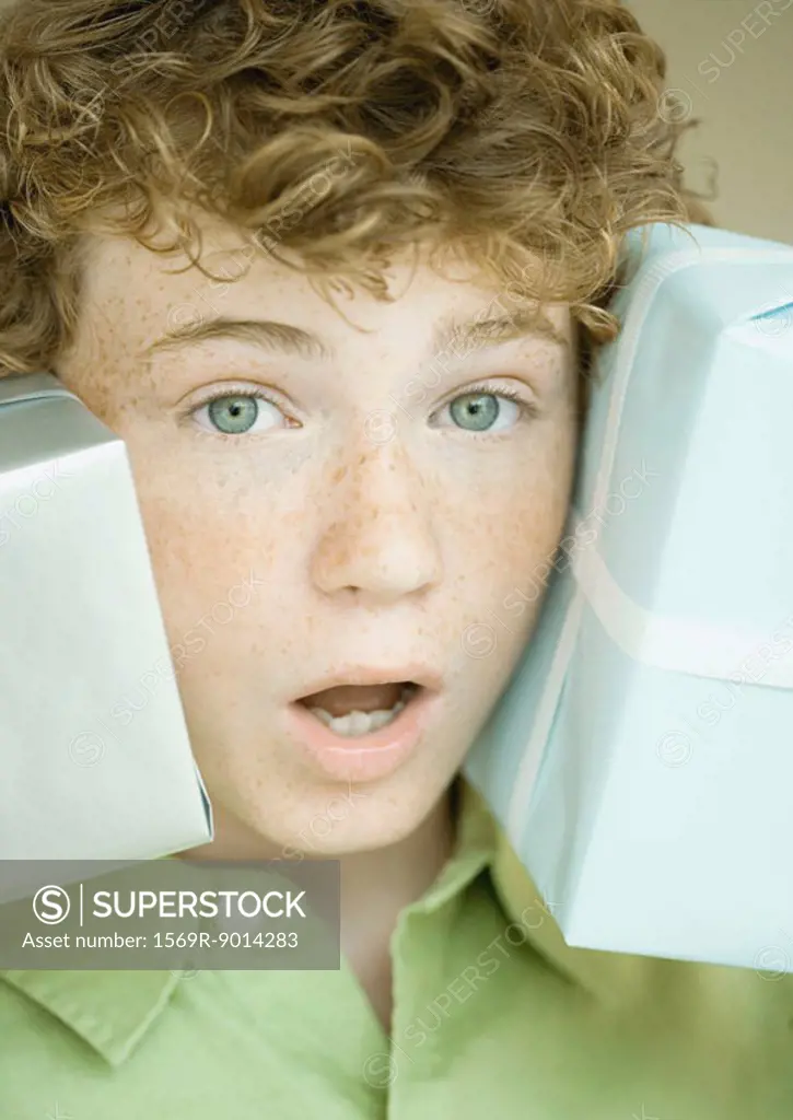 Boy holding up presents on either side of face
