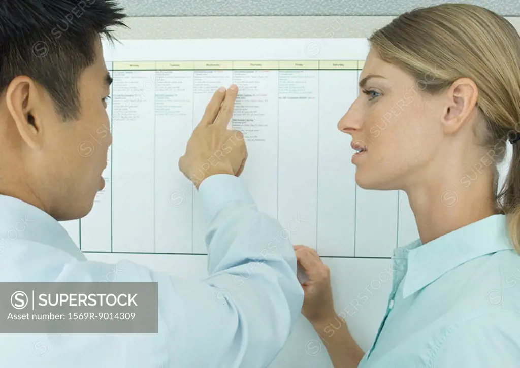 Two office workers looking at chart on wall