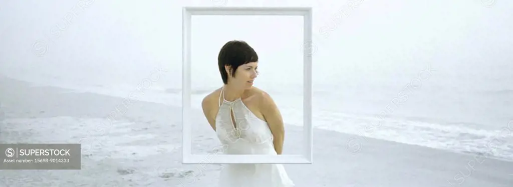 Woman standing on beach, behind frame