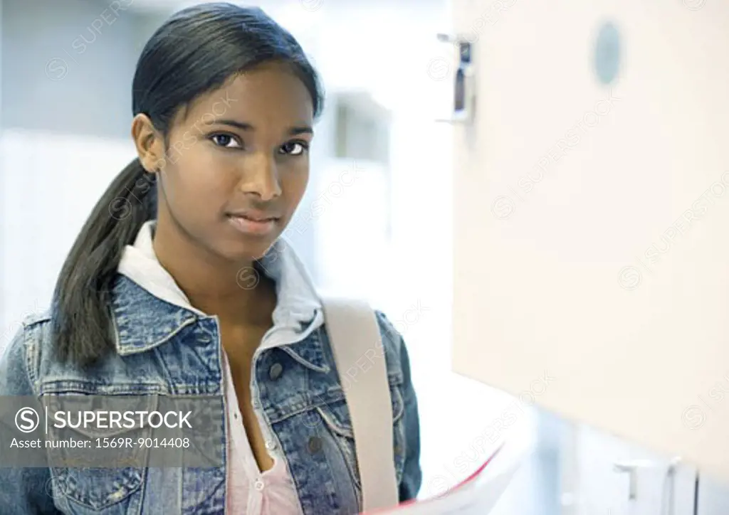 Teen girl standing by locker