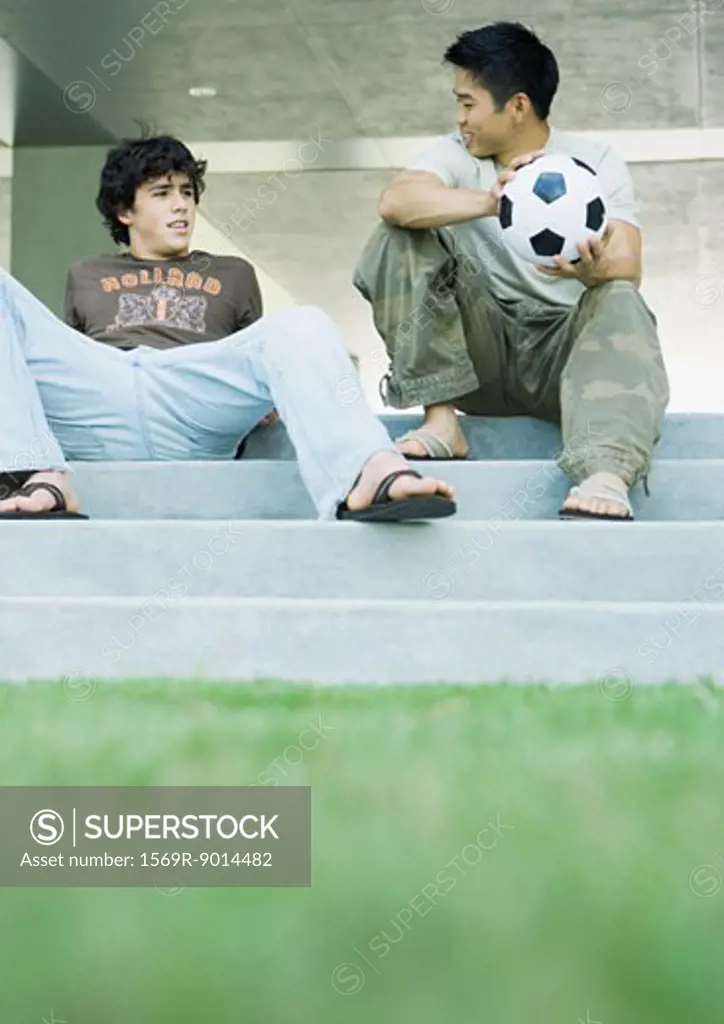 Two male college students sitting on steps, talking