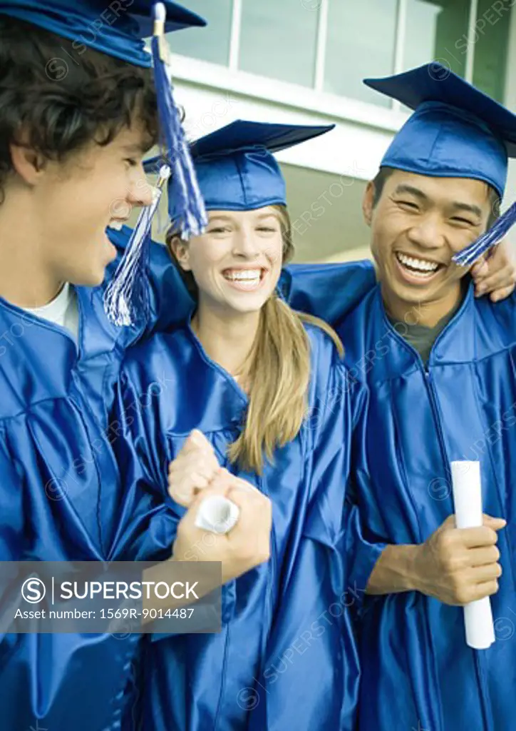 Graduates holding diplomas and laughing