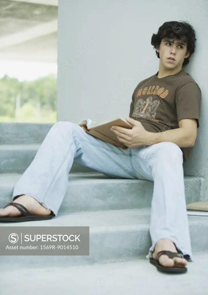 Young man sitting on steps with book