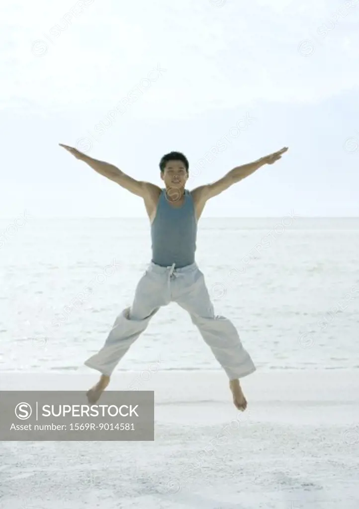 Man jumping spreadeagled on beach
