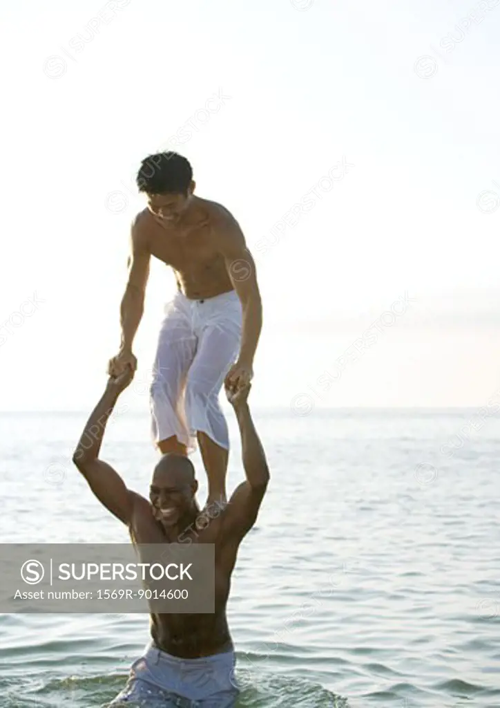 In sea, man standing on second man's shoulders