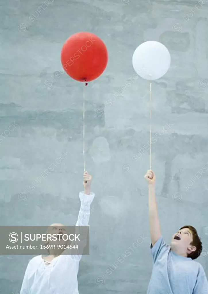 Two children holding balloons and making faces
