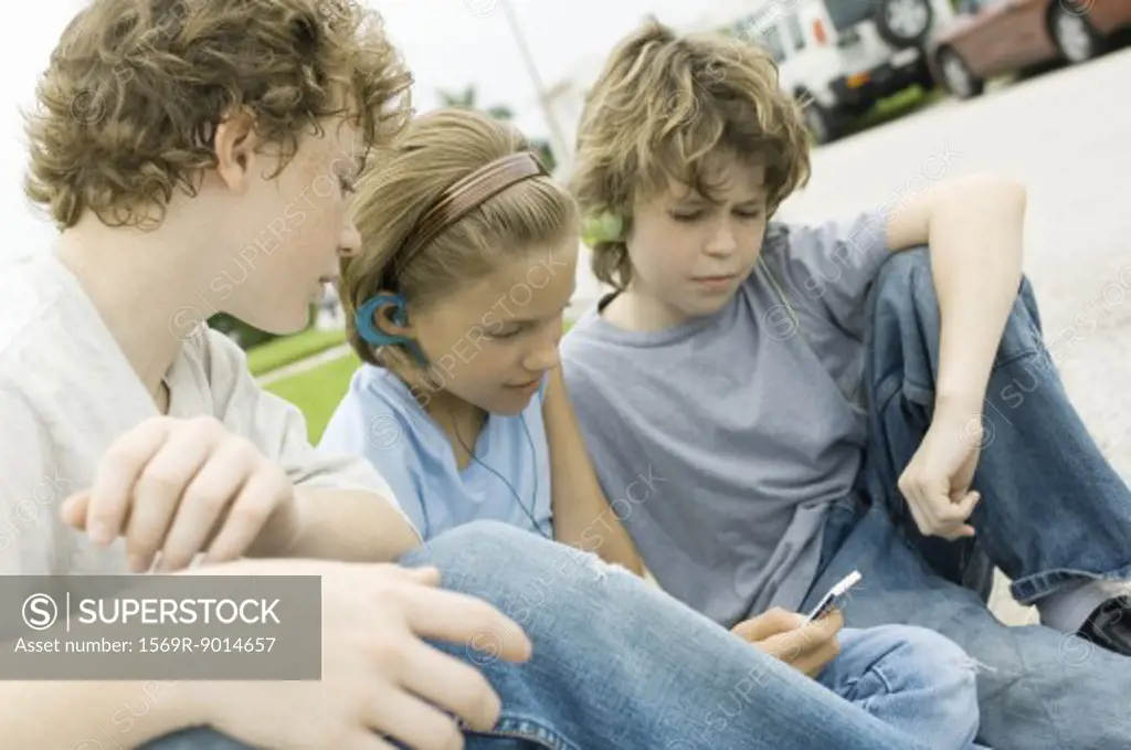 Children sitting in street, one with mp3 player