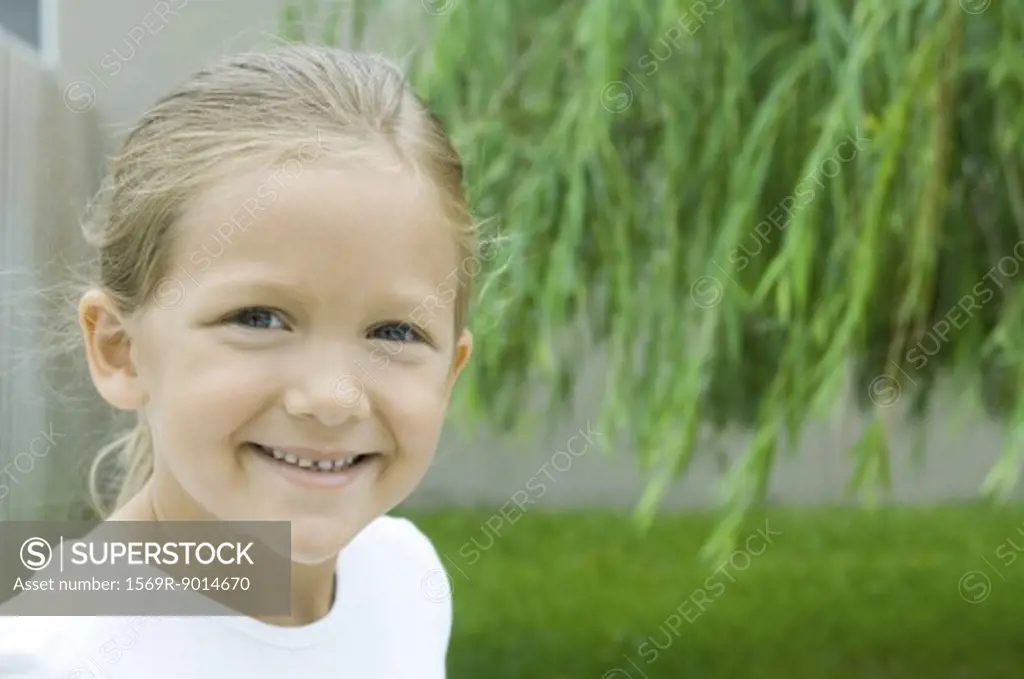Girl smiling in backyard, portrait