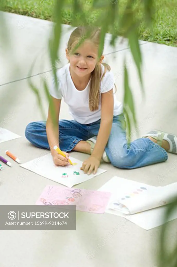 Girl sitting on driveway, drawing