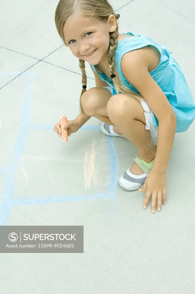 Girl drawing hopscotch game on driveway