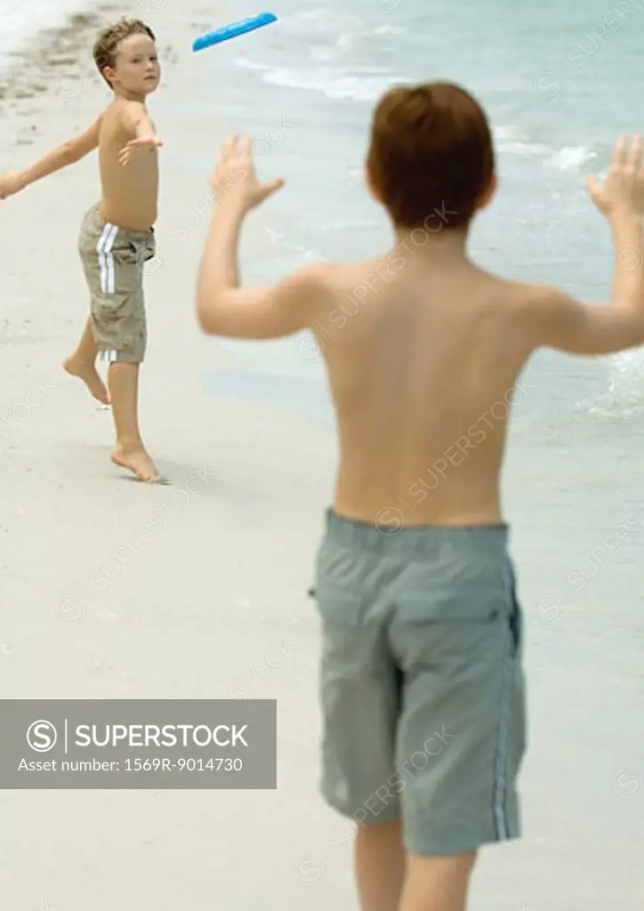 Boys throwing frisbee on beach