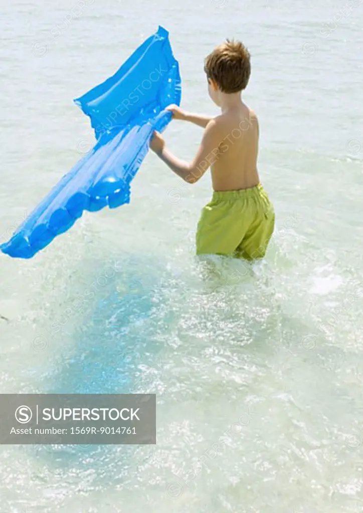 Boy carrying air mattress in sea