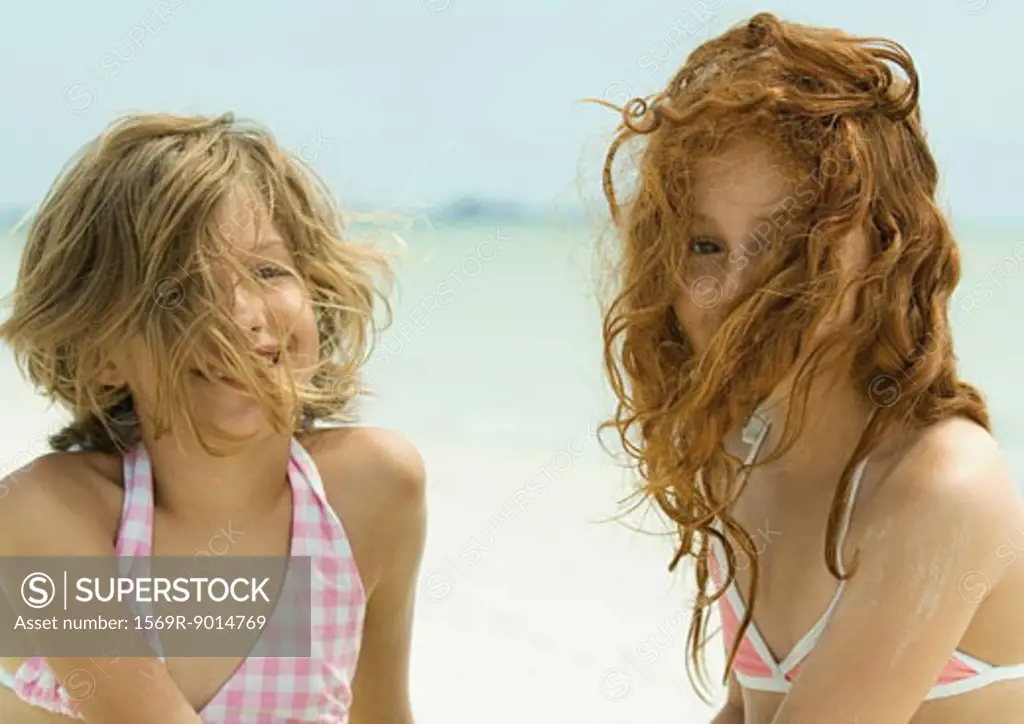 Two girls on the beach with hair in front of faces