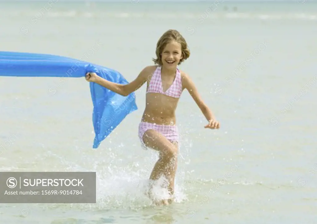 Girl running in surf with air mattress