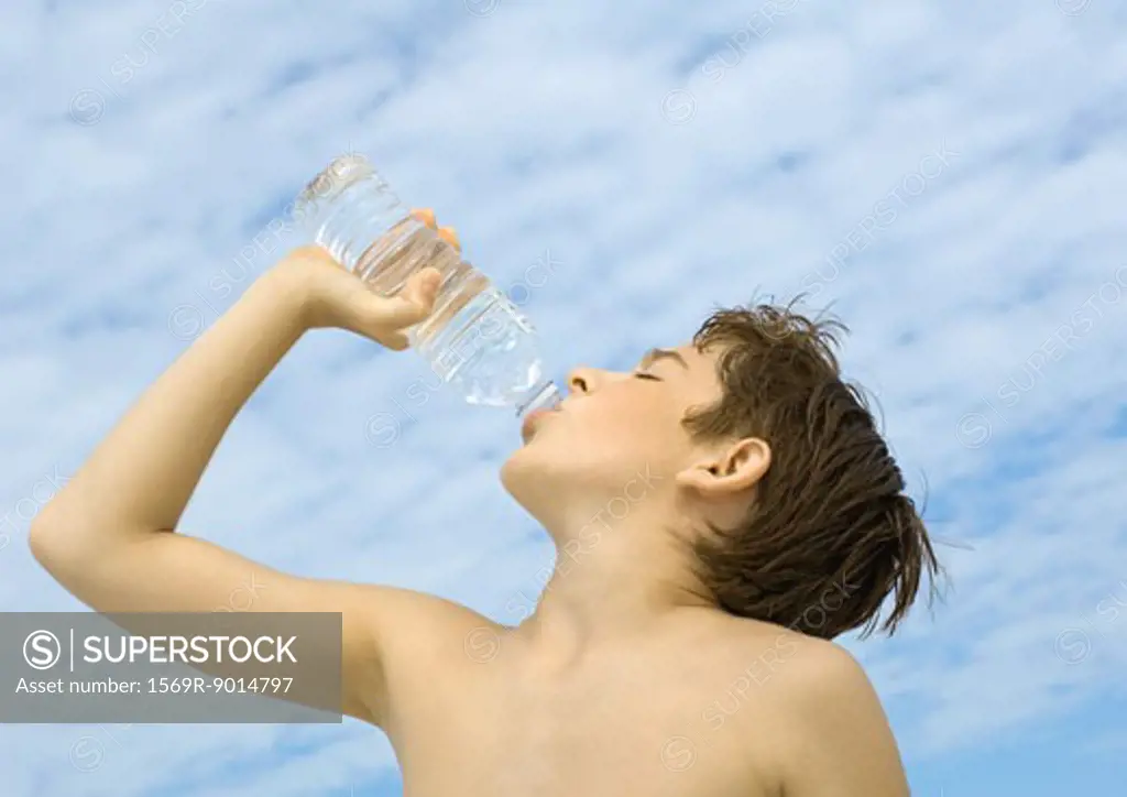 Boy drinking water from bottle, low angle view