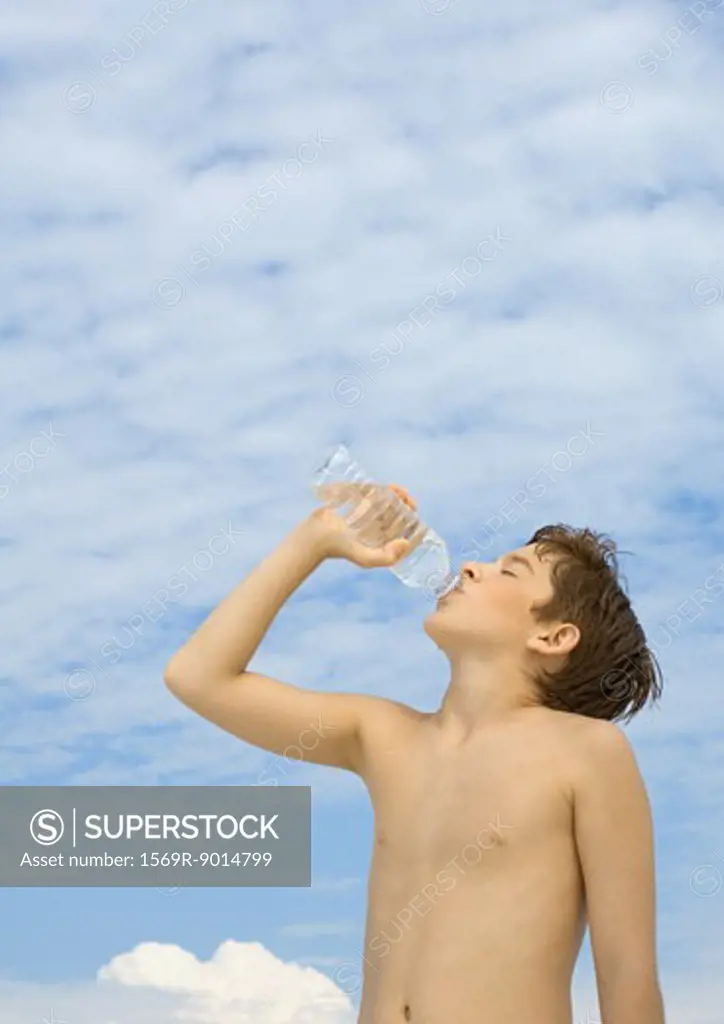 Boy drinking water from bottle, low angle view