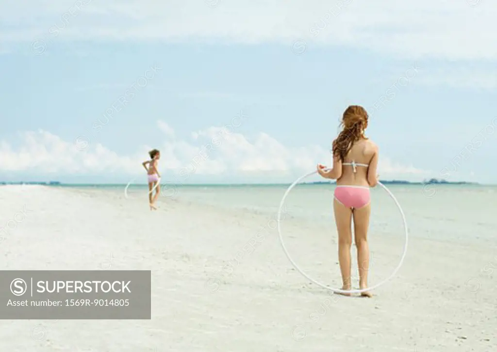 Girls playing with hoola hoops on beach