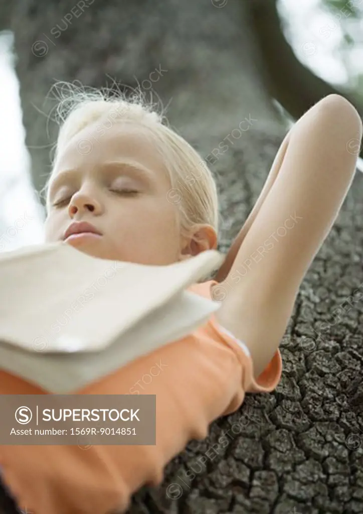 Girl in tree sleeping with book on chest