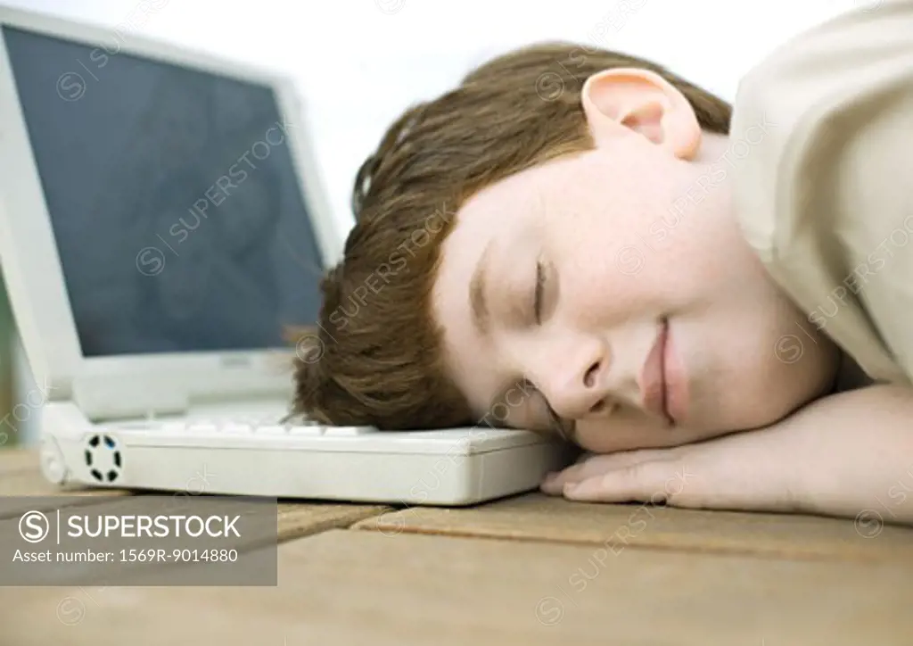 Boy sleeping with head on laptop