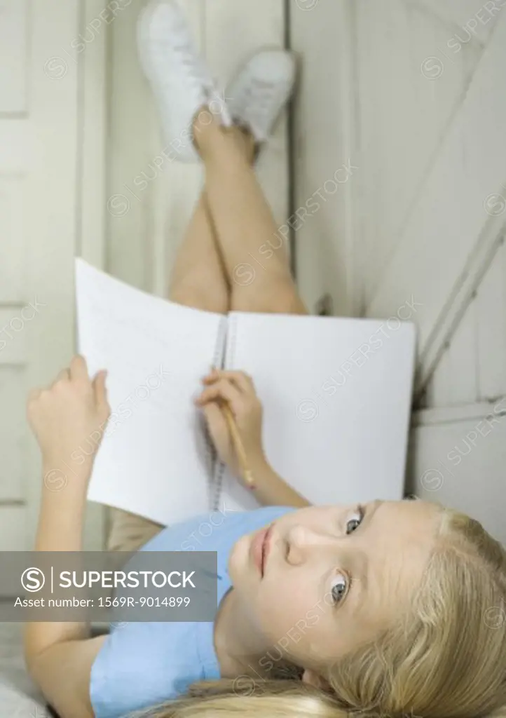 Girl studying, lying on back with legs up