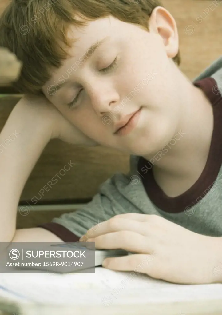 Boy dozing off as he does homework