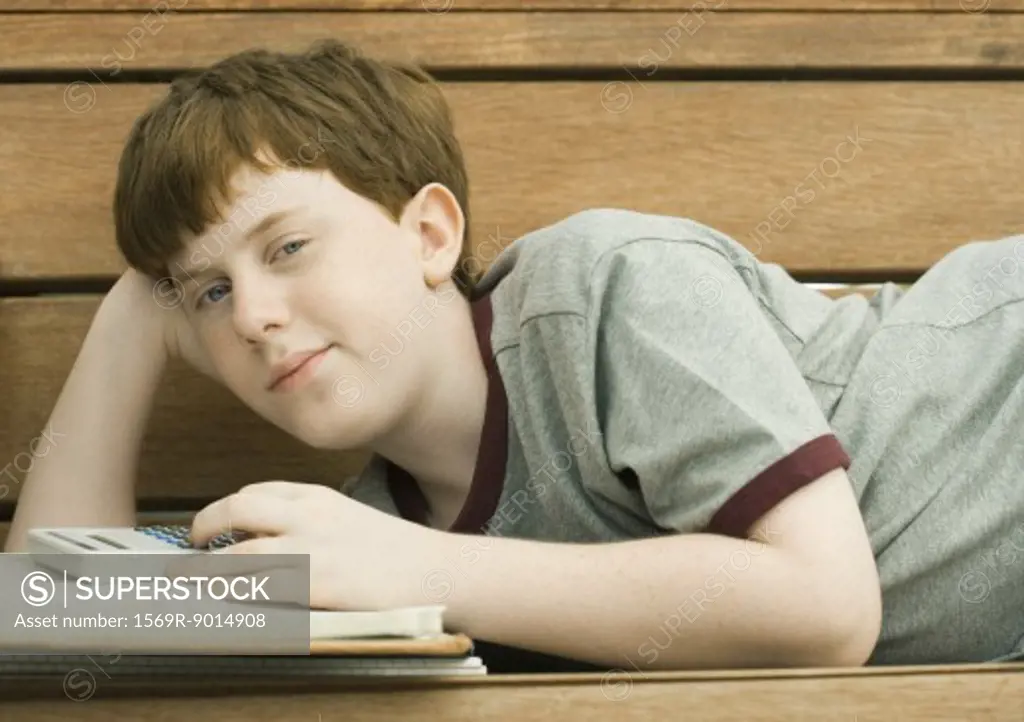 Boy lying on bench with homework