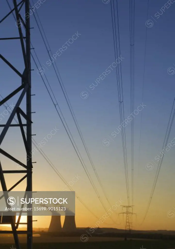 Nuclear cooling towers and electric wires and pylon at sunset 