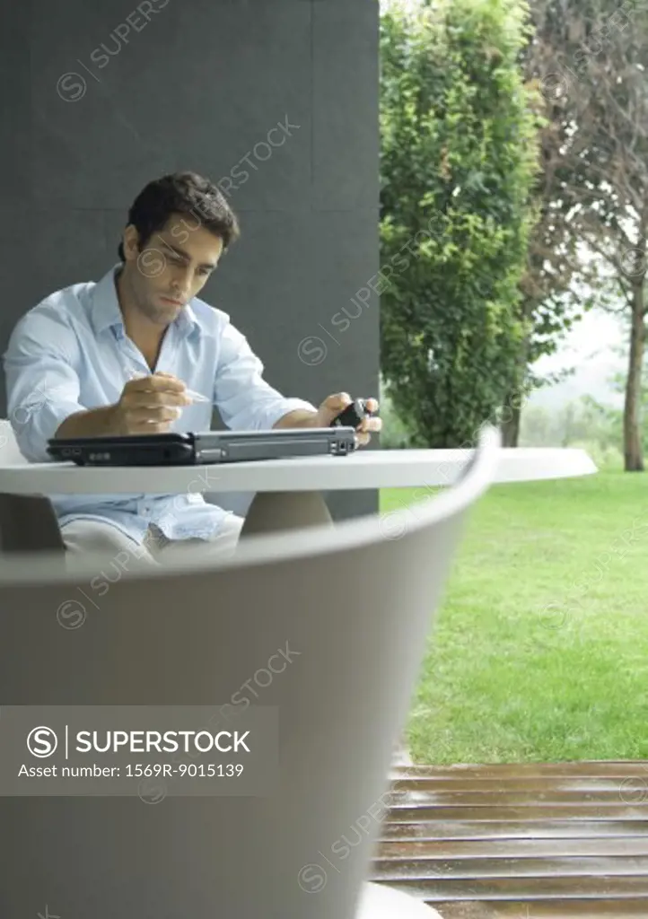 Man sitting at table outdoors, working