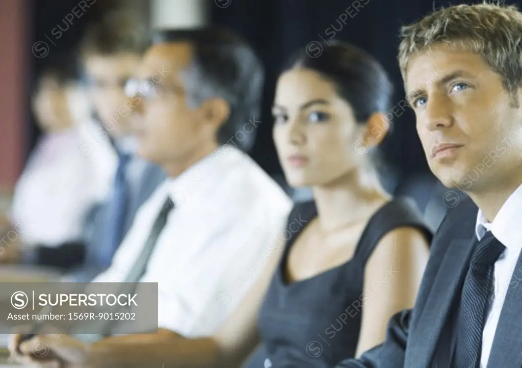 Businesspeople sitting, looking attentively out of frame