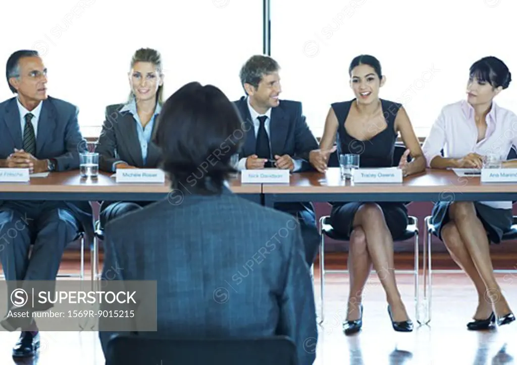 Businesspeople in committee meeting, facing man in foreground