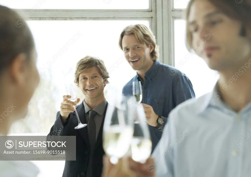 Men holding up glasses of champagne during cocktail party
